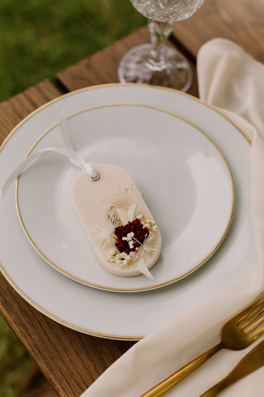 Decorative plate with a small dish and a decorative sachet on a wooden table.