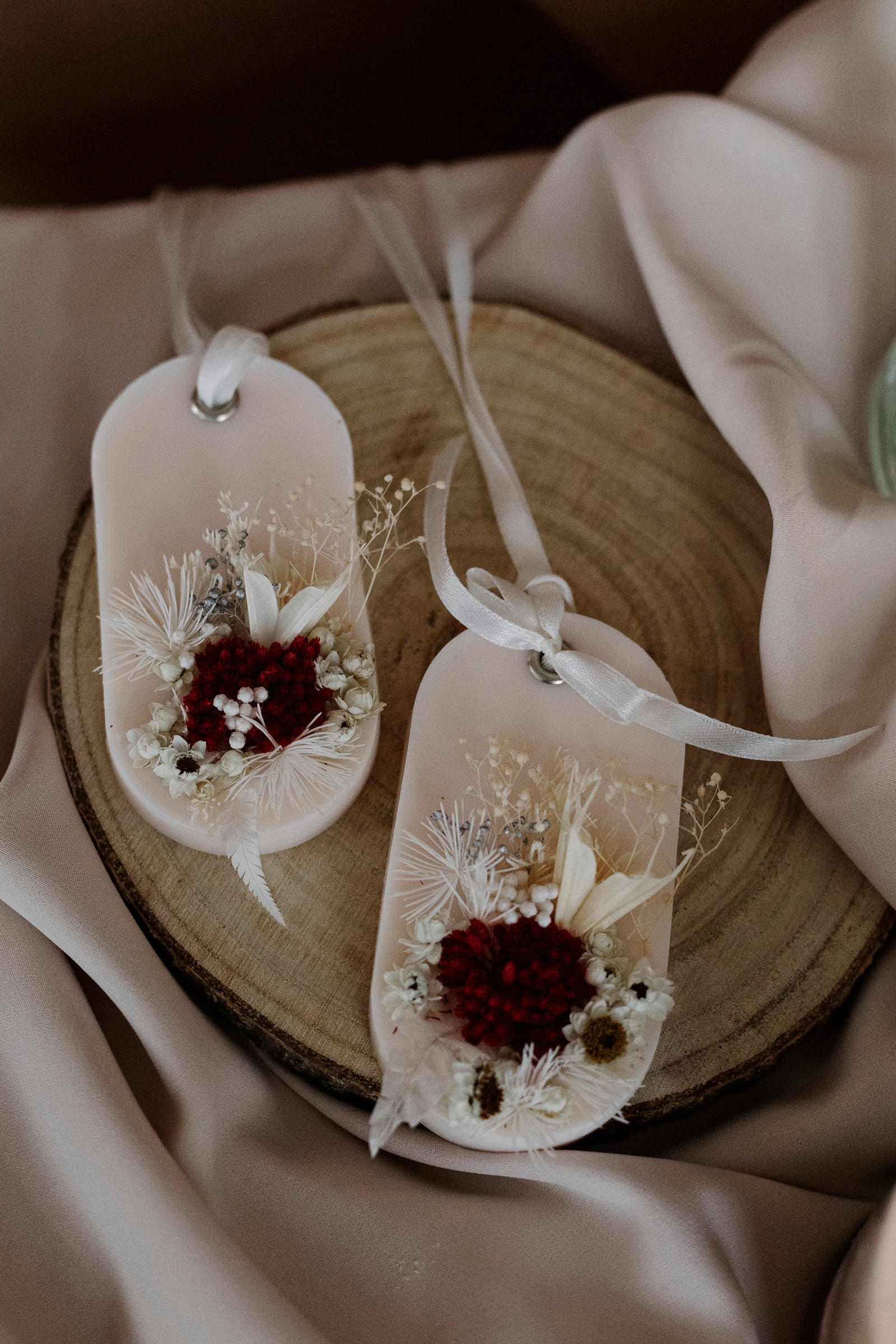 Decorative scented sachets as guest favors with floral arrangements on a wooden surface