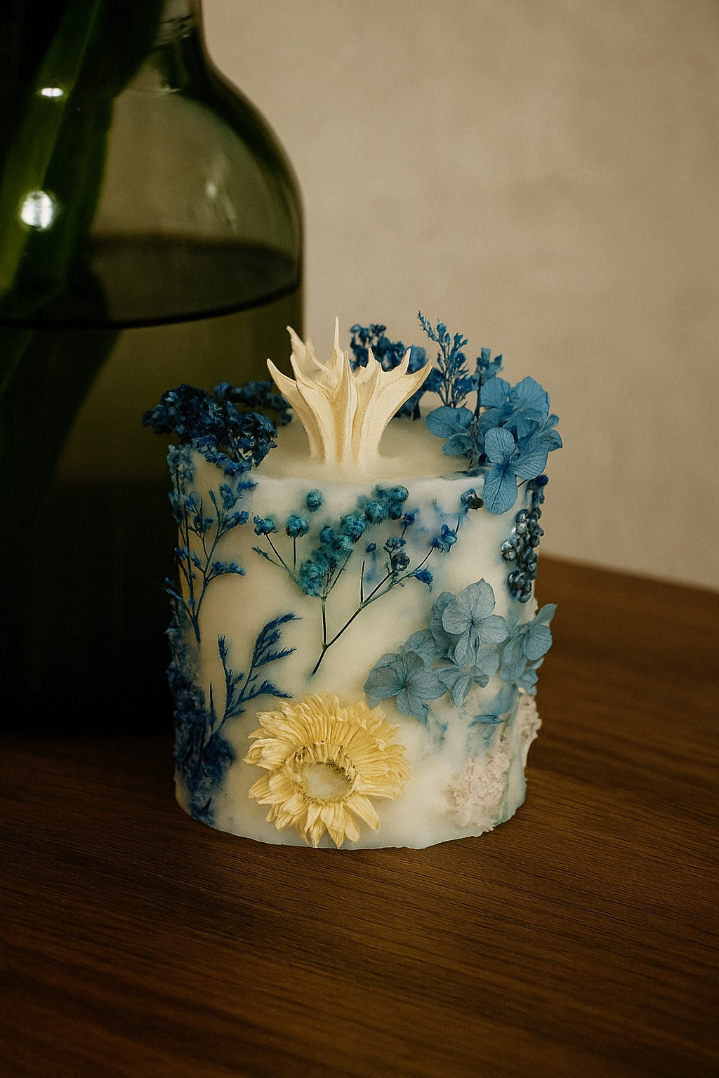 Decorative candle with blue and yellow flowers on a wooden surface