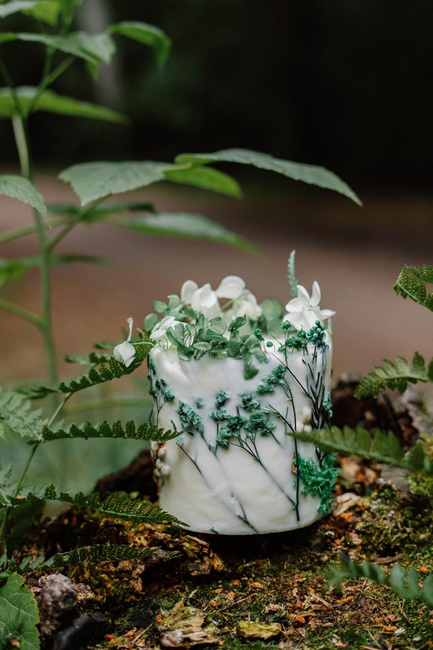 Botanical green candle with greenery on a natural background