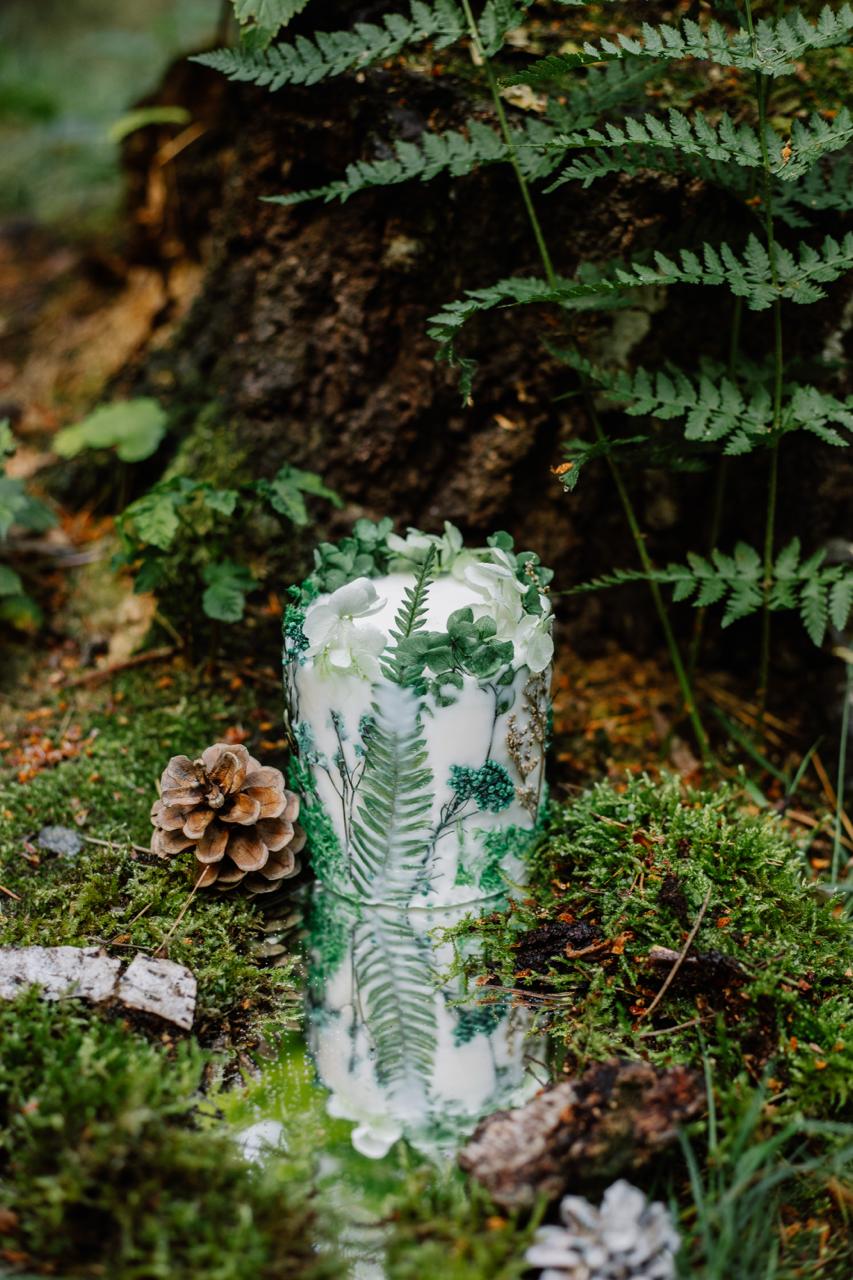 Botanical candle with greenery on a forest floor