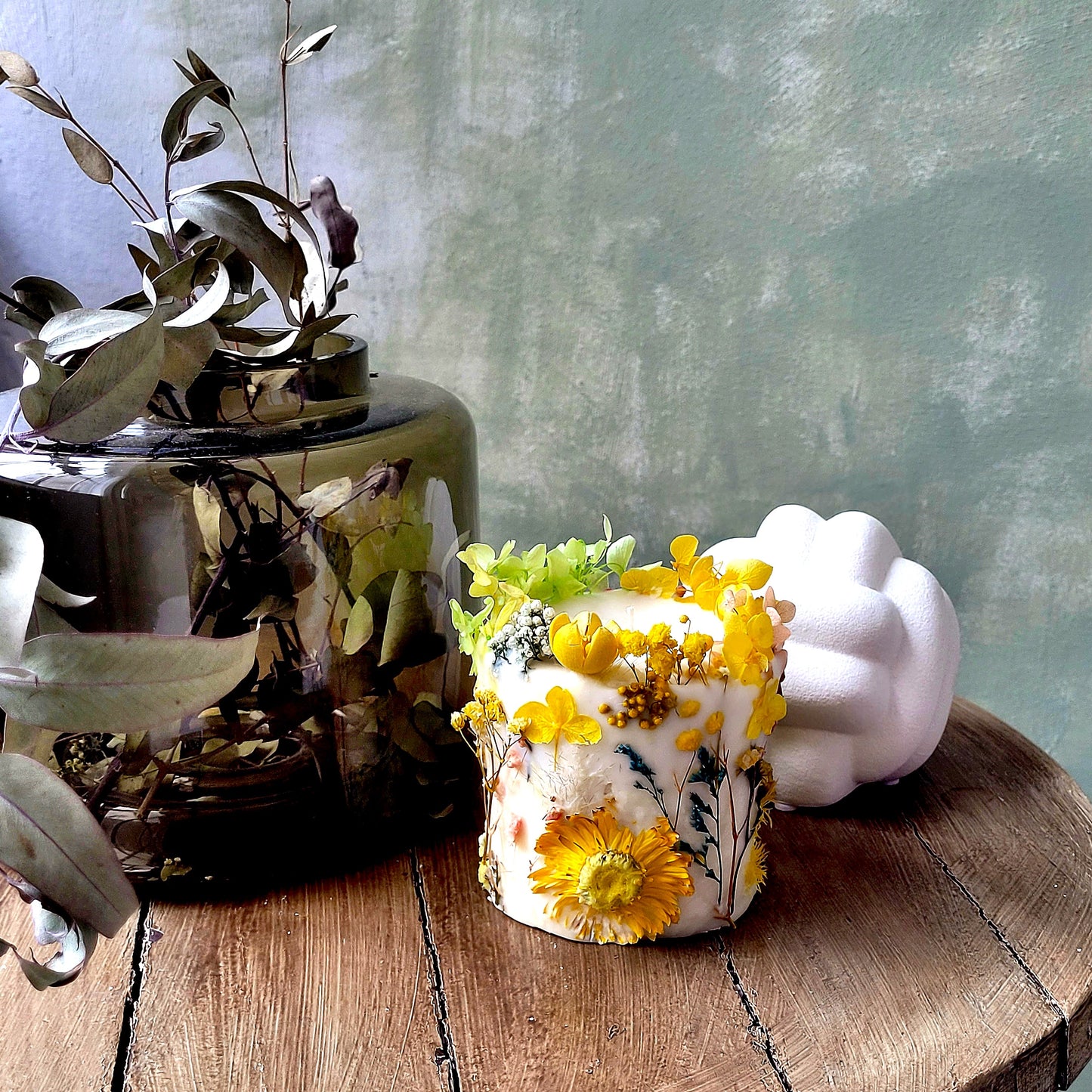Decorative botanical candle with floral design on a wooden surface with a blurred background