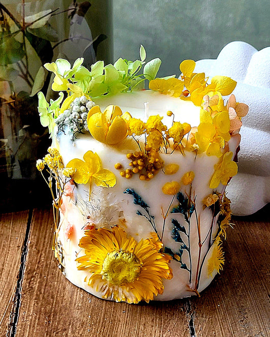Decorative botanical candle with yellow flowers on a wooden surface