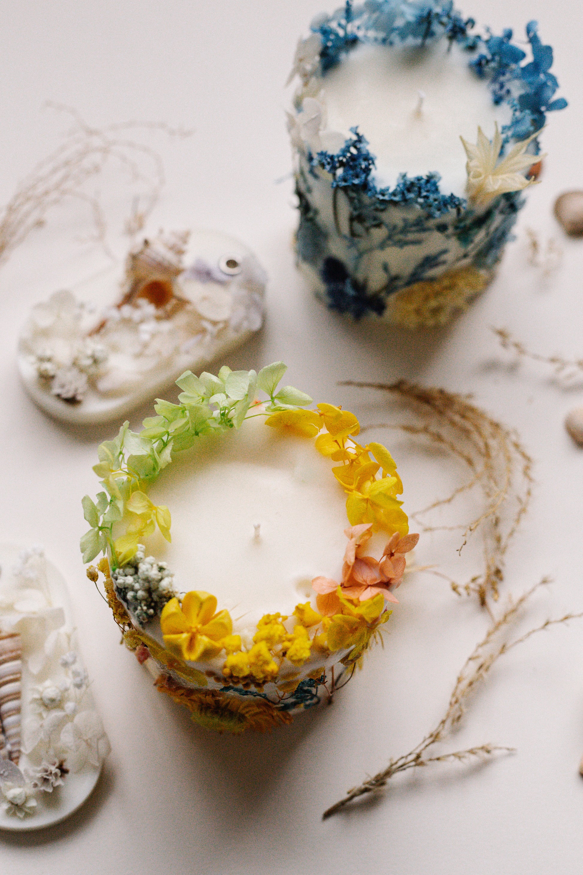 Decorative candles with floral wreaths on a white surface