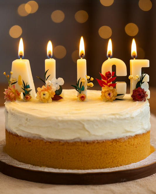 Birthday cake with lit candles with Alice-name custom candles against a blurred bokeh background