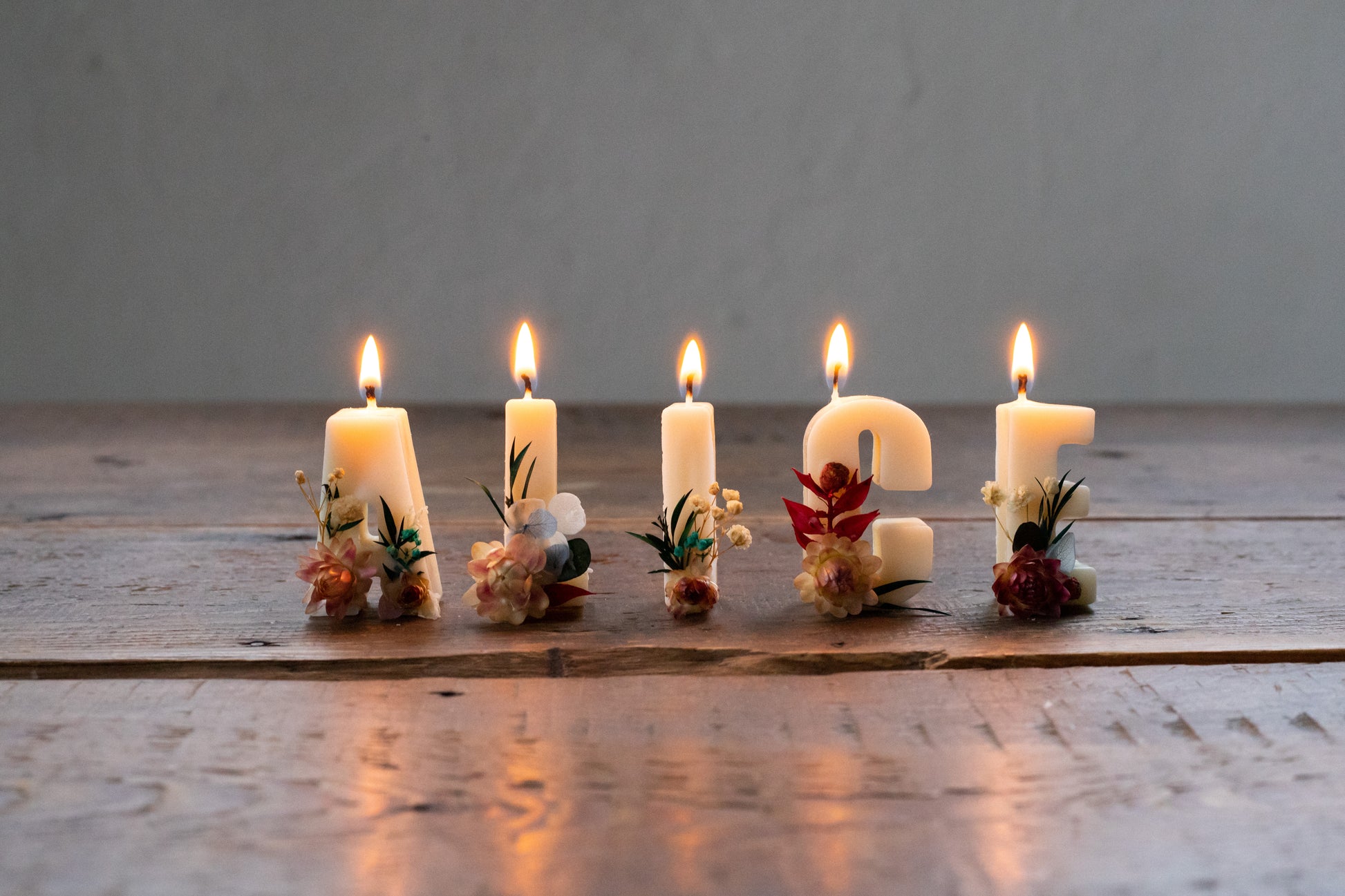 Hand-made soy wax letter candles embedded in wooden stand