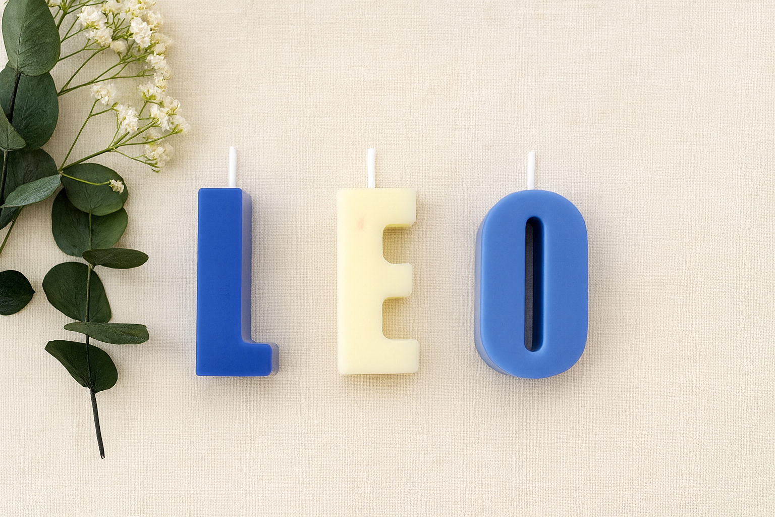 Hand-poured multicoloured soy wax letter candles on the white floral background
