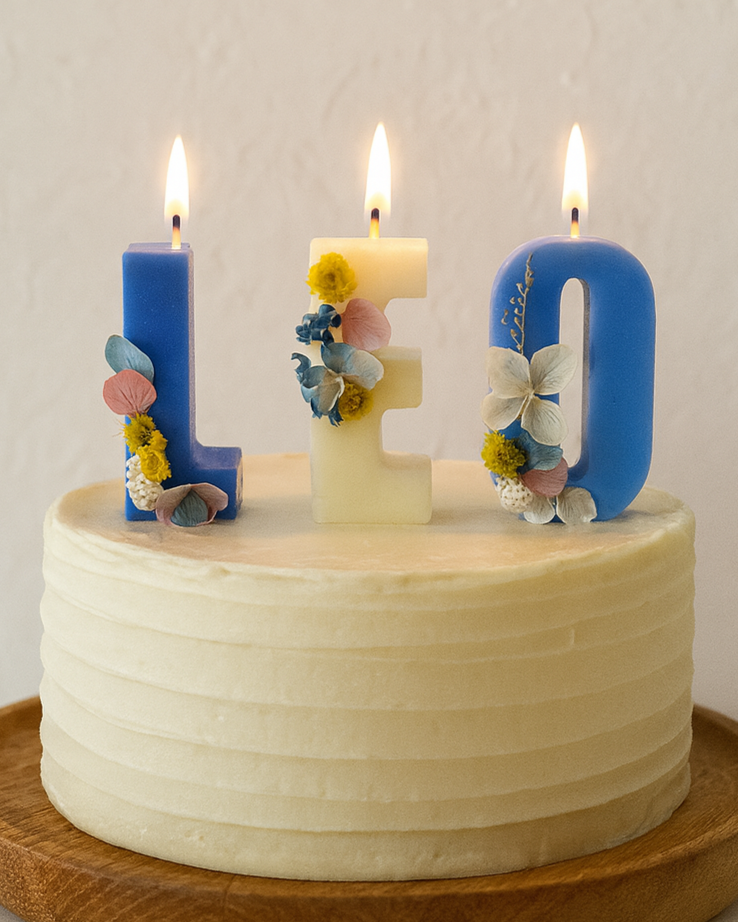 Decorative birthday cake with letter-shaped candles spelling 'LOVE' on a plain background
