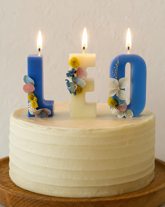 Decorative birthday cake with letter-shaped candles spelling 'LOVE' on a plain background