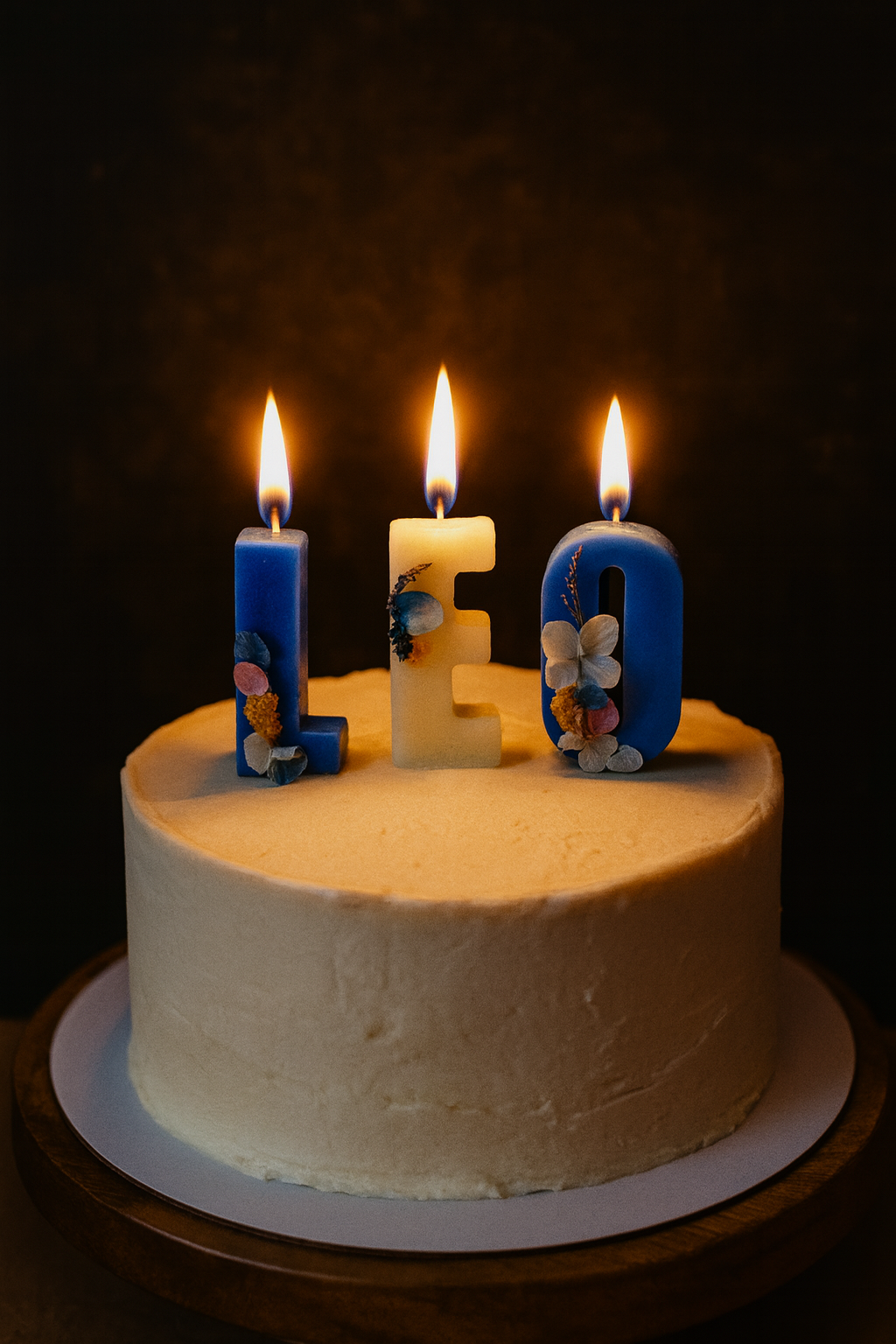 White cake with 'LEO' candles on a dark background