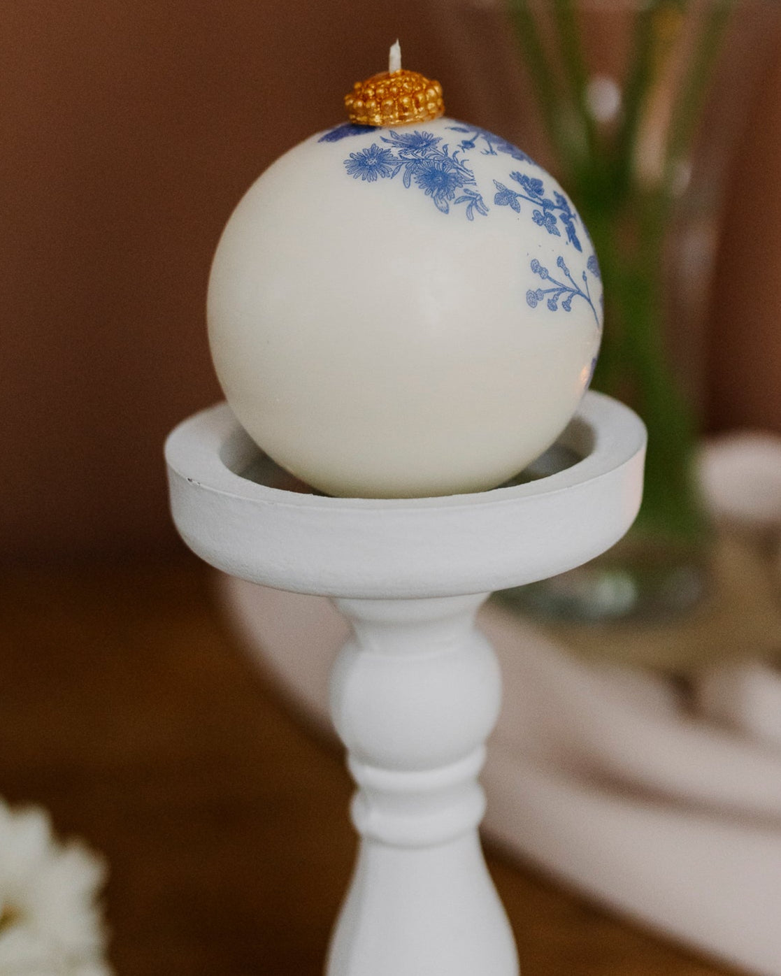 Decorative candle with floral design on a white candlestick against a blurred background