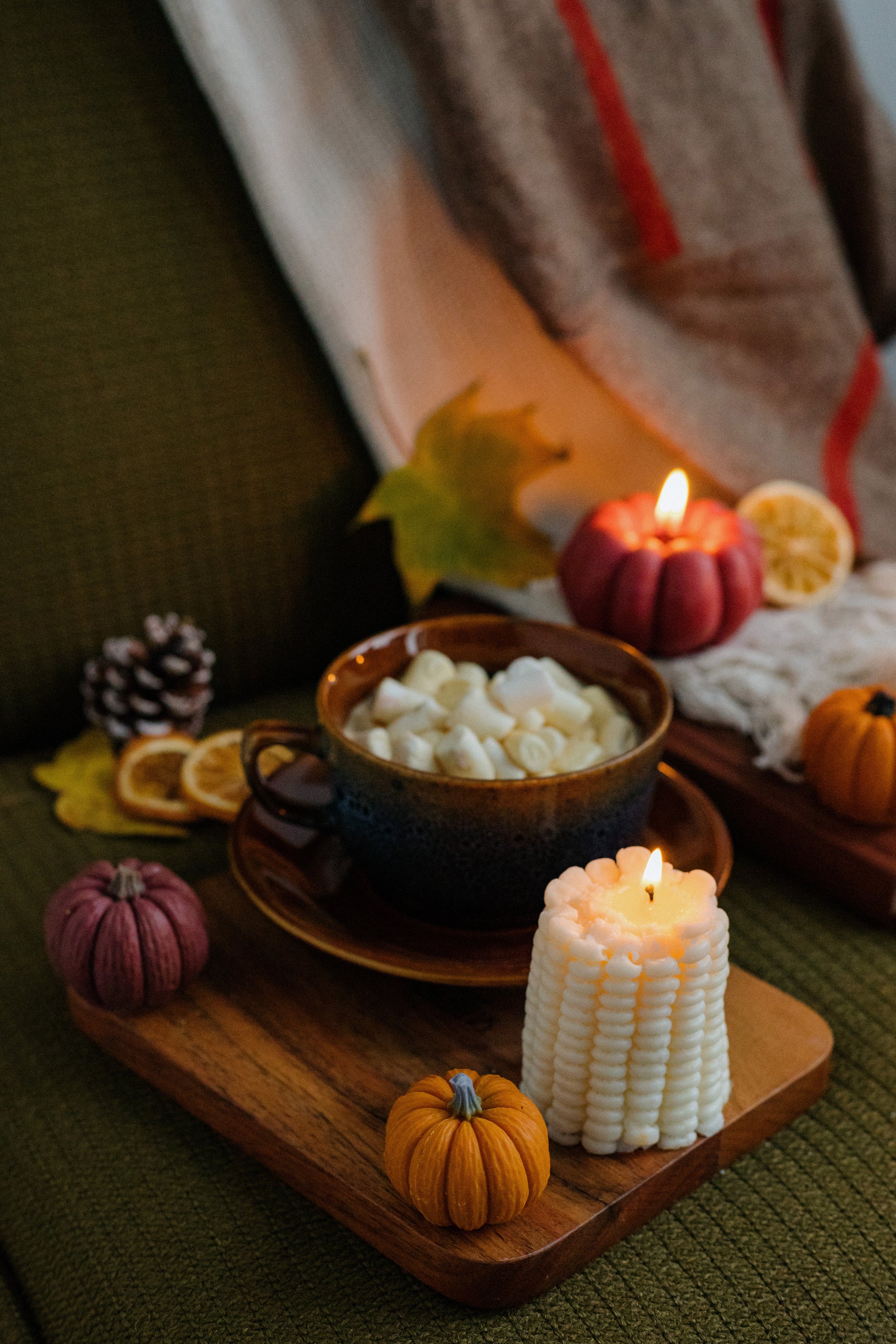 Cozy autumn scene with a bowl of marshmallows, candles, and fall decorations on a wooden tray.