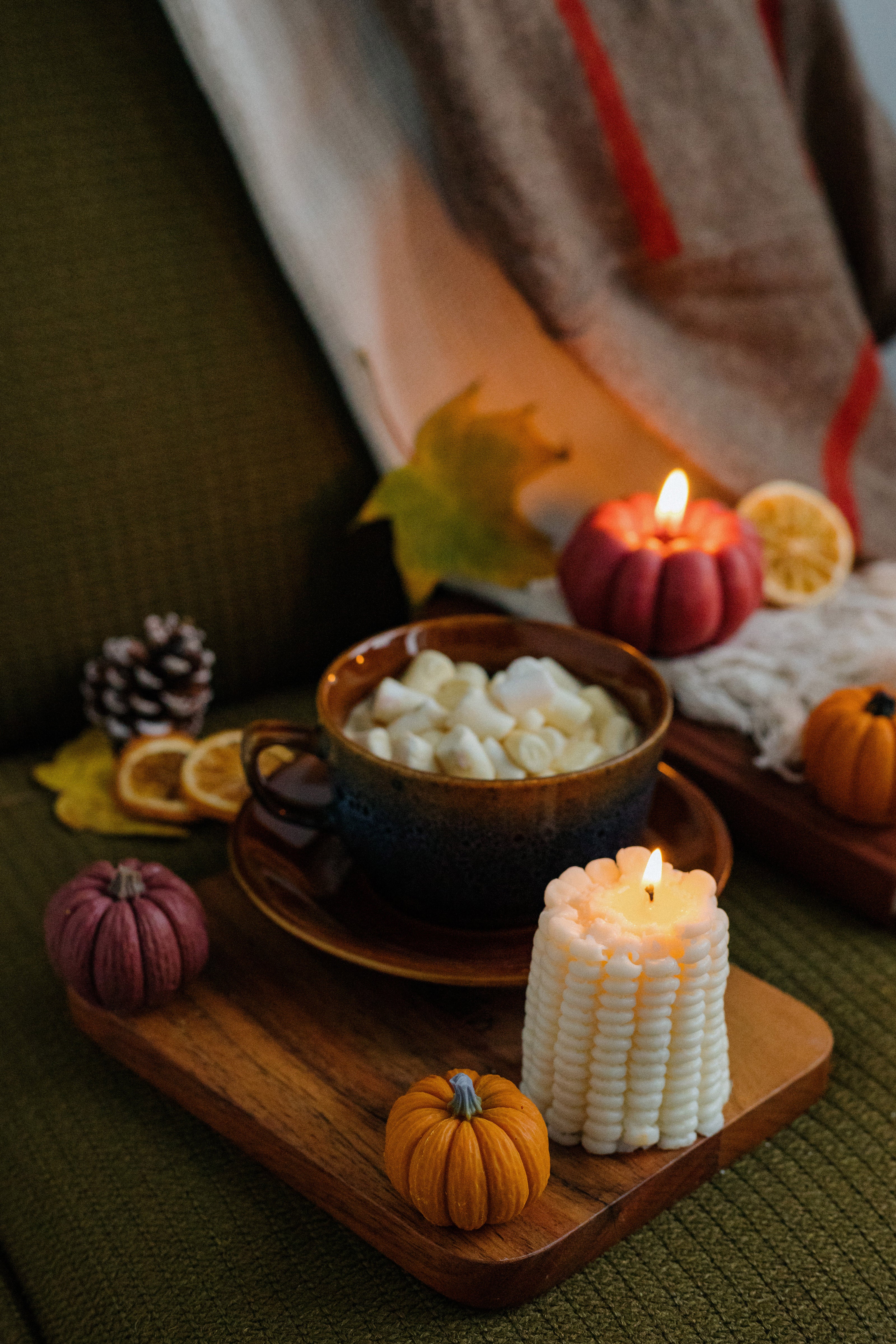Cozy autumn scene with a bowl of marshmallows, candles, and fall decorations on a wooden tray.