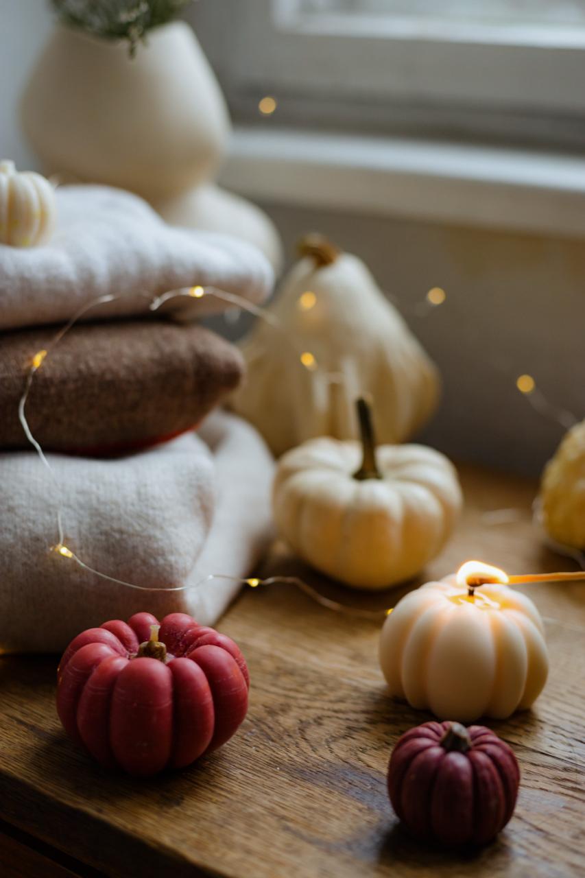 Pumpkin candles of different colors on the wooden table